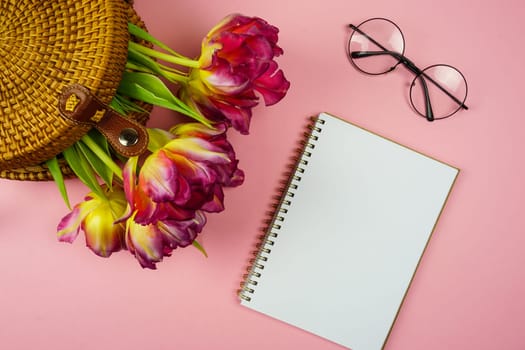 a notebook for notes and pink tulips in a wicker bag. High quality photo