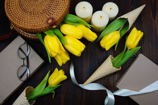 Yellow tulips comfortably laid out on the table in a wicker bag and in waffle cones. High quality photo