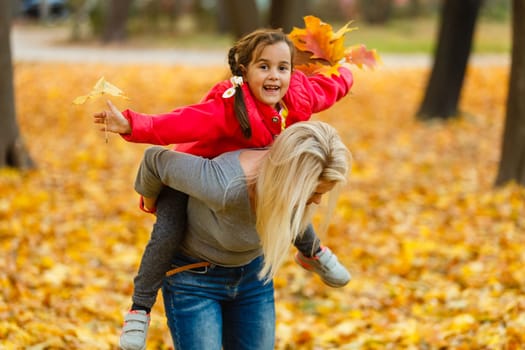 mother and daughter in the city park in autumn having fun time