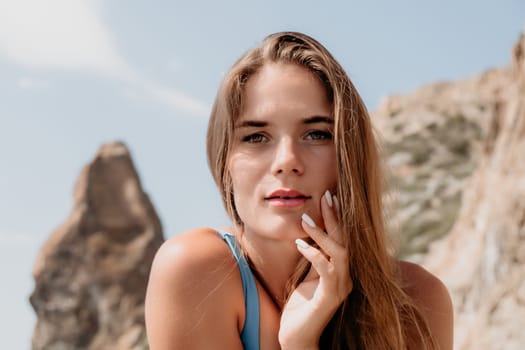 Woman travel sea. Young Happy woman in a long red dress posing on a beach near the sea on background of volcanic rocks, like in Iceland, sharing travel adventure journey