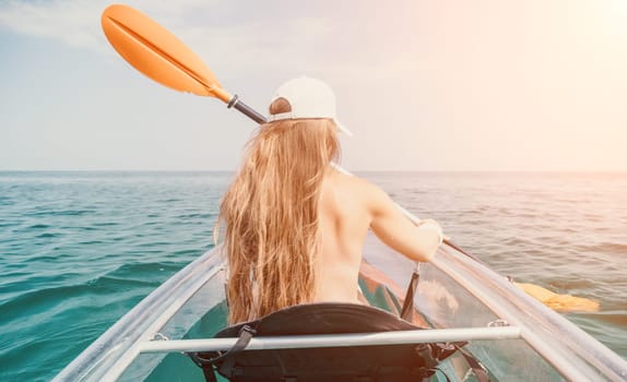 Woman in kayak back view. Happy young woman with long hair floating in transparent kayak on the crystal clear sea. Summer holiday vacation and cheerful female people having fun on the boat.