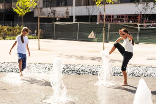 life of children in a modern city - little girl having fun with fountains. High quality photo