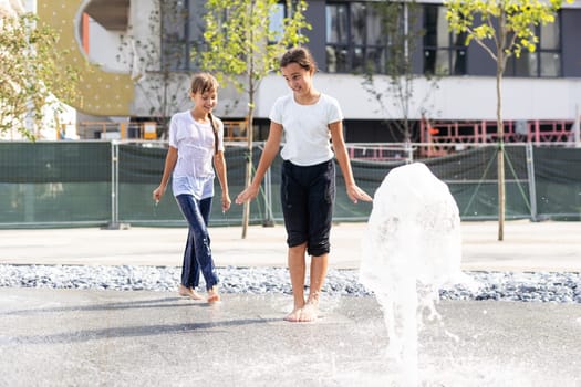 Little girls cool off in a fountain on a hot summer day. High quality photo