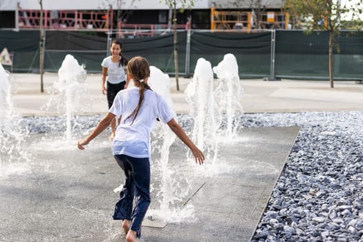 On a hot day, children run and have fun at the city fountain. Leisure time concept. summer holidays. happy childhood. High quality photo