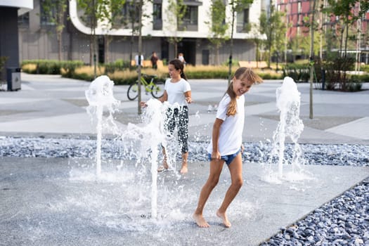 Little girls cool off in a fountain on a hot summer day. High quality photo