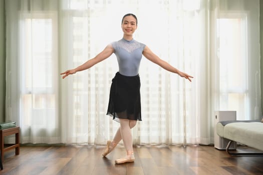 Full length portrait of beautiful woman practicing ballet at home. Dance, art and active lifestyle concept.