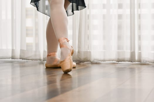 Close up classic ballerina legs in pointe shoes on the wooden floor. Dance, art and active lifestyle concept.