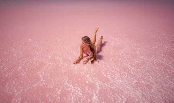 Woman in a pink salt lake. She lies in a white bathing suit. Wanderlust photo for memory.