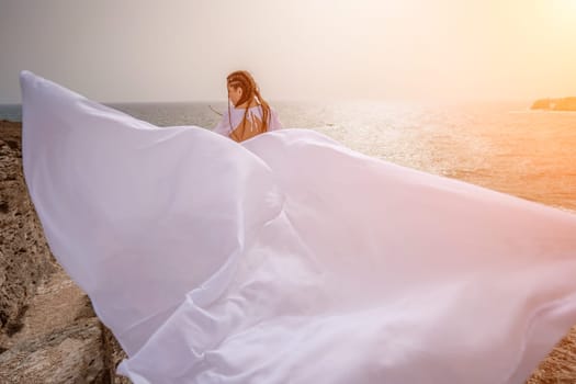 Woman sea white dress. Happy freedom woman on the beach enjoying and posing in white dress. Rear view of a girl in a fluttering white dress in the wind. Holidays, holidays at sea