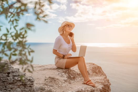 Freelance women sea. She is working on the computer, talking on the phone in the open air with a beautiful view of the sea. The concept of remote work