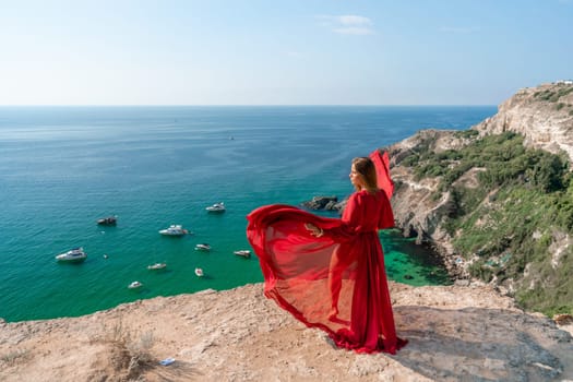 Red Dress Woman sea Cliff. A beautiful woman in a red dress and white swimsuit poses on a cliff overlooking the sea on a sunny day. Boats and yachts dot the background