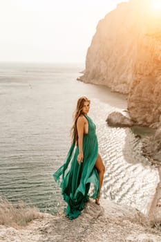 Woman sea trevel green dress. Side view a happy woman with long hair in a long mint dress posing on a beach with calm sea bokeh lights on sunny day. Girl on the nature on blue sky background