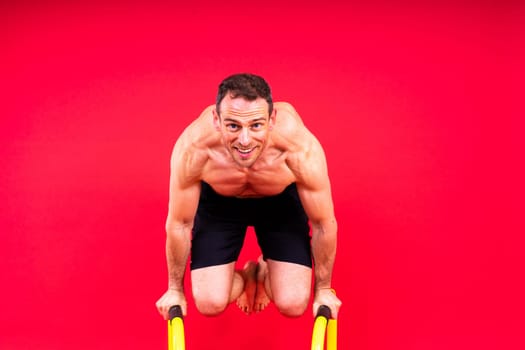 Front and side view photo of strong young man exercising on parallel bars in studio.