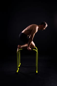 Front and side view photo of strong young man exercising on parallel bars in studio.