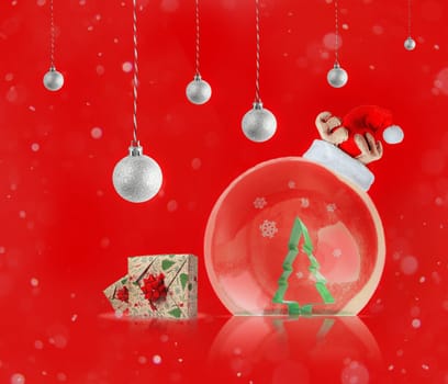 Transparent ball with green tree and Santa Claus hat, gift boxes on abstract red background. Festive New Year backdrop for posters and cards.