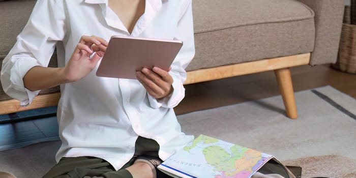 Young traveler woman using laptop to book a hotel and search for tourist attraction information while prepare travel suitcase before going on summer vacation. Online booking concept.