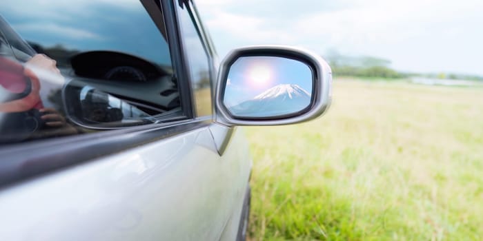 Reflection of a gorgeous Mount Fuji in a side mirror of a car while parking to take photos concept travelling driving rest.