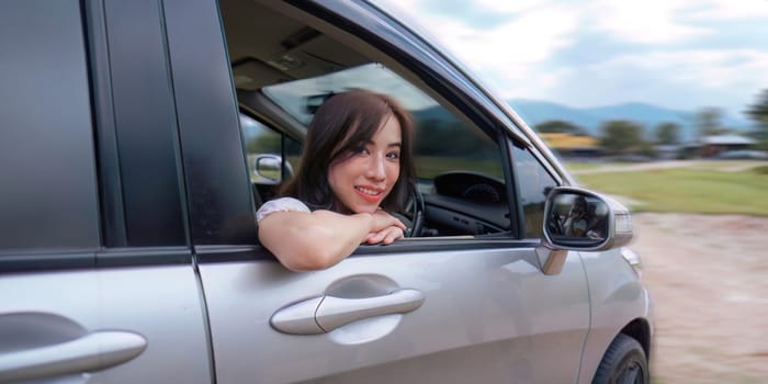 Young smiling woman park the car to car before trip and smiling at camera.