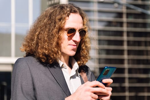 portrait of a young entrepreneur man using mobile phone outdoors at the financial district, concept of technology of communication and urban lifestyle, copy space for text