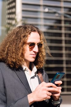 portrait of a young entrepreneur man using mobile phone outdoors at the financial district, concept of technology of communication and urban lifestyle, copy space for text