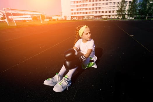 Female child boxer in gloves, feminism concept. Back to school, physical training.