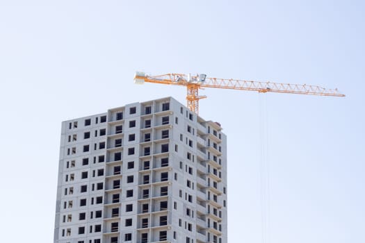 Tower crane and construction of a tall apartment building close up