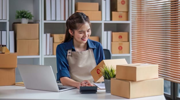 Portrait business Asian woman smile checking information on parcel shipping box before send to customer. Entrepreneur small business working at home. SME business online marketing..