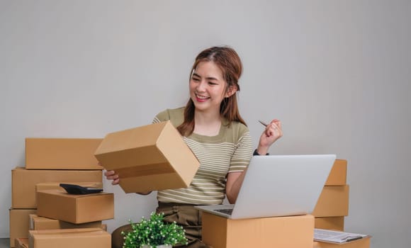 Happy young Asian woman entrepreneur, Smile for sales success after checking order from online.
