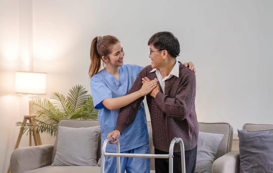 young asian female nurse care giver helping asian senior old man with mobility walker in living area of nursing home senior daycare center. Nurse take care elderly patient with cheerful concentrate.