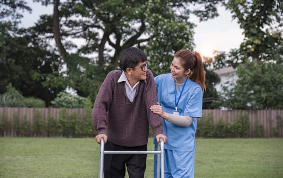 Asian woman caregiver helping senior man walking. Nurse assisting he old man patient at nursing home. Senior man using walker being helped by nurse at home. Elderly patient care and health lifestyle.