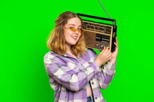Happy young caucasian woman using retro tape record player to listen music, disco dancing favorite track, having fun, entertaining, fan of vintage technologies. Girl isolated on chroma key background