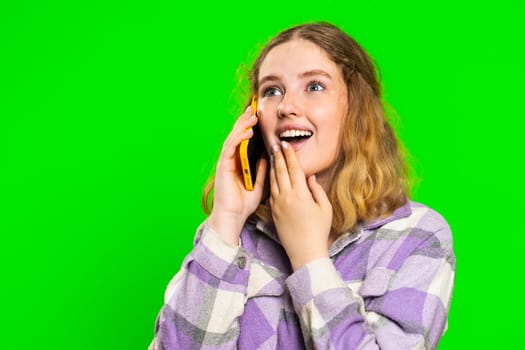 Phone call, good news, gossip. Happy surprised young caucasian woman involved in pleasant conversation on smartphone, enjoying talking with friend. Redhead girl isolated on green chroma key background