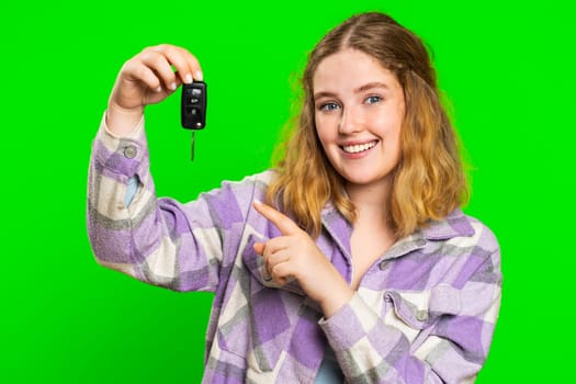 Confident smiling young caucasian woman buyer showing key of new car, auto business, purchase vehicle, success sale, renting, buying. Happy excited redhead girl isolated on green chroma key background