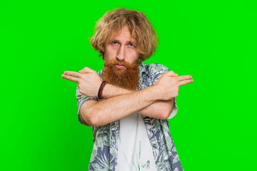 Young bearded man pointing around with finger gun gesture, looking confident making choice shooting killing with hand pistol right on target. Guy isolated on green chroma key background. Advertisement