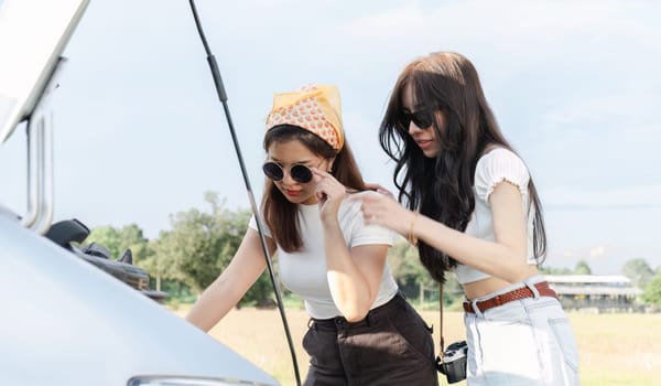 Two young Asian women waiting for insurance assistance I'm stressed out about my car having problems. While traveling together.