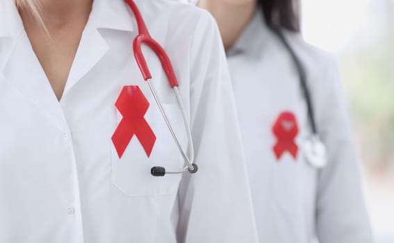 Two doctors in white coat with red ribbon on their chest. AIDS and hiv prevention and treatment concept