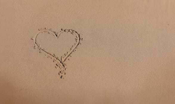 Drawn heart on wet sand next to sea. Love for the sea and travel concept