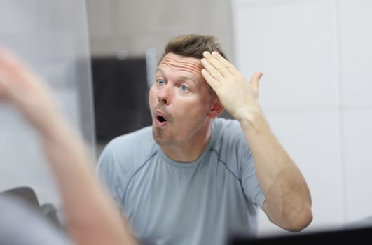 Narcissistic man in front of mirror does his hair. Psychological portrait of male narcissist concept
