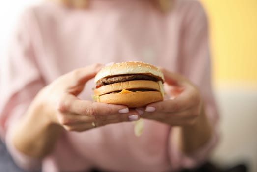 Female hands hold hamburger with cheese and meat. Fast delivery and takeaway food concept