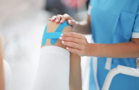 Doctor fixes kinesio tape on patient's leg. Kinesio tapes - pain relief without drugs concept