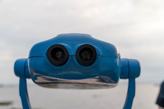 Metal blue stationary outdoor binoculars on the observation deck overlooking the sea. paid binoculars for tourists to view the sights.