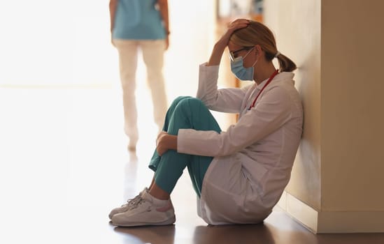 Frustrated doctor sits in hospital corridor. Medical error and accident concept