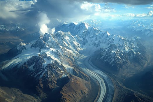 Aerial view of snow-capped mountain range and low hanging clouds.