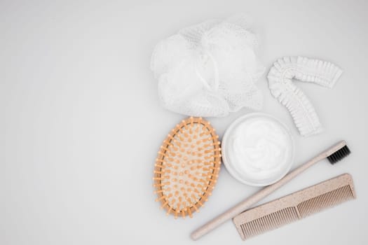 Flat lay of bath essentials. Wooden brush, cream, toothbrush, comb, and exfoliating pads.