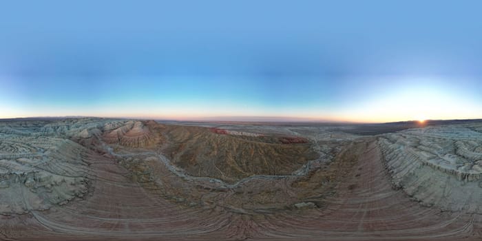 The sun sets, casting a warm glow over the colorful, eroded ridges and vast expanse of the painted desert, creating a breathtaking panorama