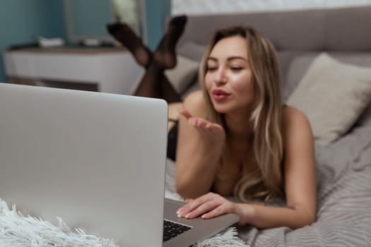 A beautiful, young girl shoots a webcam, blows a kiss into the camera, works as a model. The concept of online flirting, sex on the Internet.