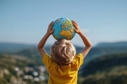 Little boy in yellow t-shirt holding globe in hands on mountain spring background. Earth day concept.