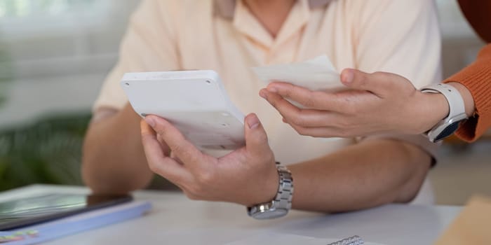 A couple holds bills and a tablet, engaged in a discussion about financial planning and managing expenses at home.