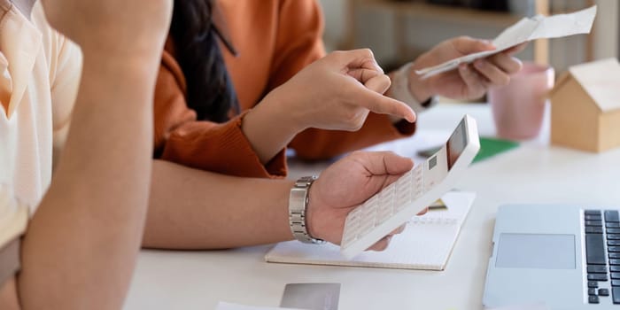 A couple engages in financial planning, discussing bills and using a calculator to manage their income effectively.