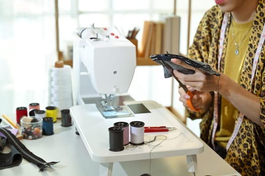 Tailor or seamstress cutting fabric with precision preparing material for sewing.
